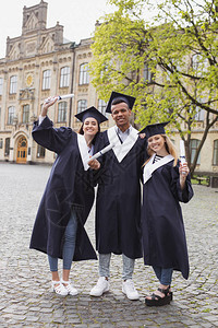 令人难忘的照片三位快乐的毕业生为拿着文凭的难忘照片摆图片