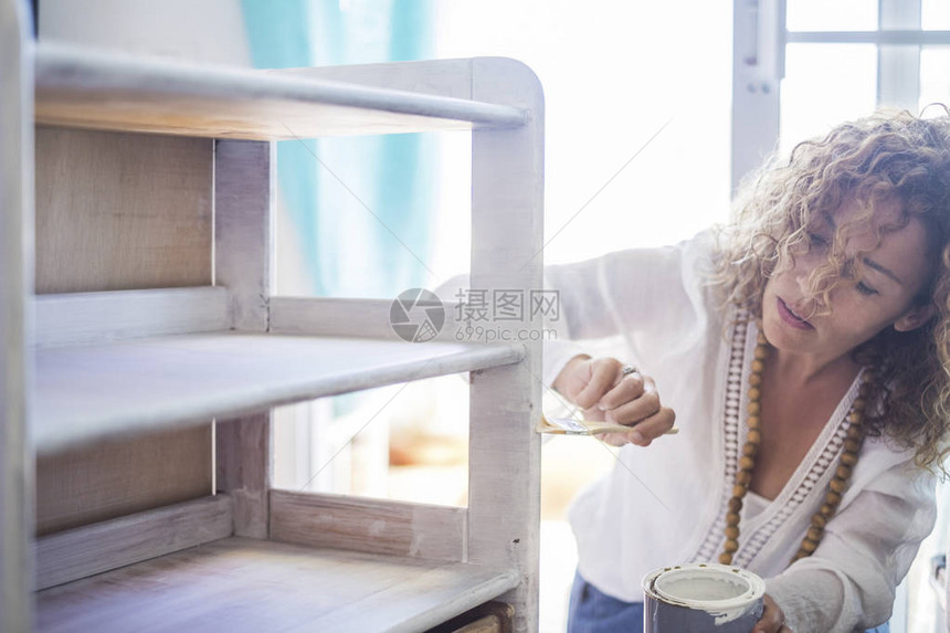 美丽的白种人中年独立女在家里用白色破旧别致的颜色粉刷和更新旧家具为孤独和立的女做自己的生活方式背图片