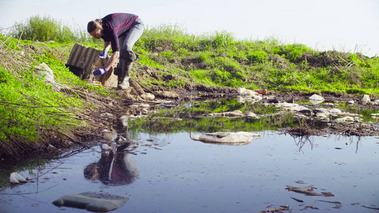 女科学家生态学家从垃圾场附近的大脏水坑抽取水样图片