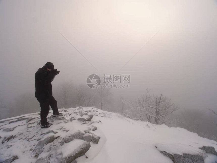 摄影师拍摄了冰雪山岩的图片极端恶劣的天气松木岩石峰值从图片