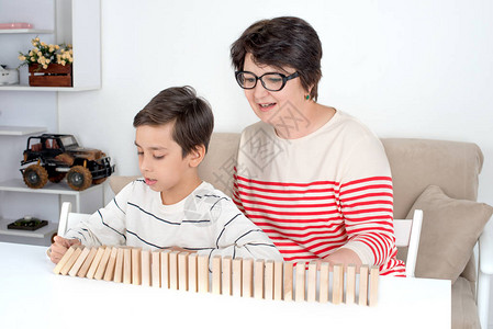 外祖母和孙子坐在桌边一起在木制图片