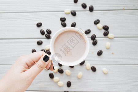 手握白杯咖啡和咖啡豆糖在木制图片