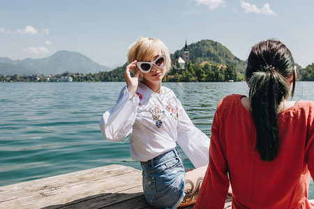 我的早更女友和女友坐在山湖的木码头上流着血斯洛维尼亚我看见她穿着背景