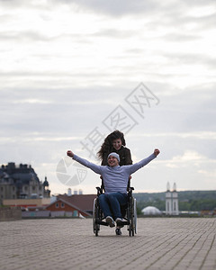 有快乐残疾男子的年轻女子坐在轮椅上图片