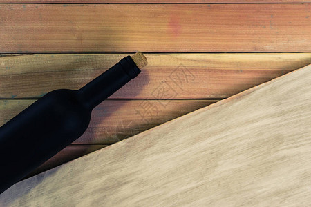 红酒的黑酒瓶子在新的红木桌上图片