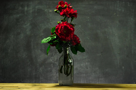 明亮的红色花园玫瑰在木制桌子图片