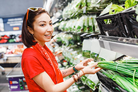 超市里的女人选择绿色蔬菜农业概念和素食图片