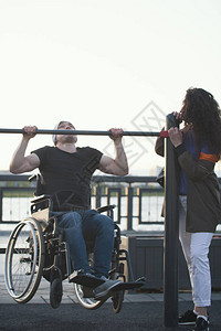 坐在轮椅上的强力残疾人男子在日落时图片