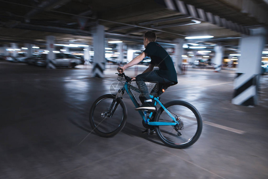 骑蓝色自行车的年轻人穿过地下停车场骑自行车的人可以在地图片