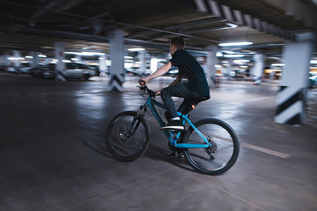 骑蓝色自行车的年轻人穿过地下停车场骑自行车的人可以在地图片