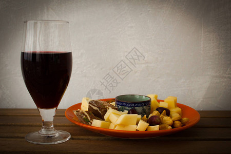一杯酒奶酪片坚果和葡萄放在木制图片