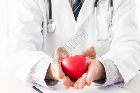有拿着红色心脏的听诊器的男医生图片