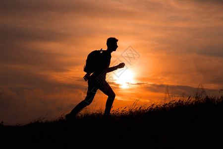 旅游男子的休光片在日落的山顶上随手张开图片