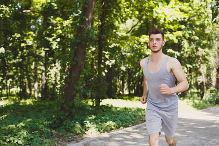 清晨锻炼时在绿色公园跑的年轻运动图片