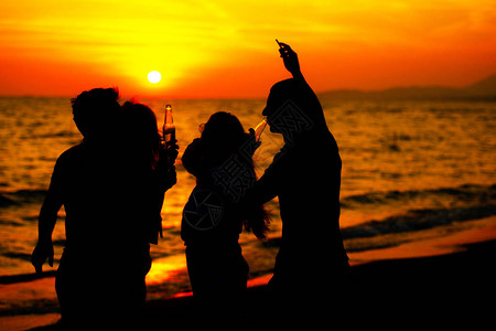 日落海滩派对上年轻人的剪影图片