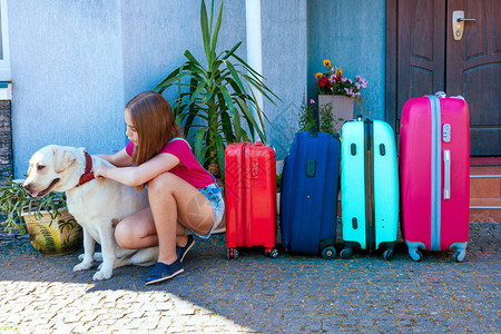 一个女孩和一只大拉布多犬靠近多色手提箱准备暑假旅行全家人与一图片