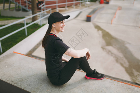 年轻微笑的运动女孩穿着黑色制服和帽子图片