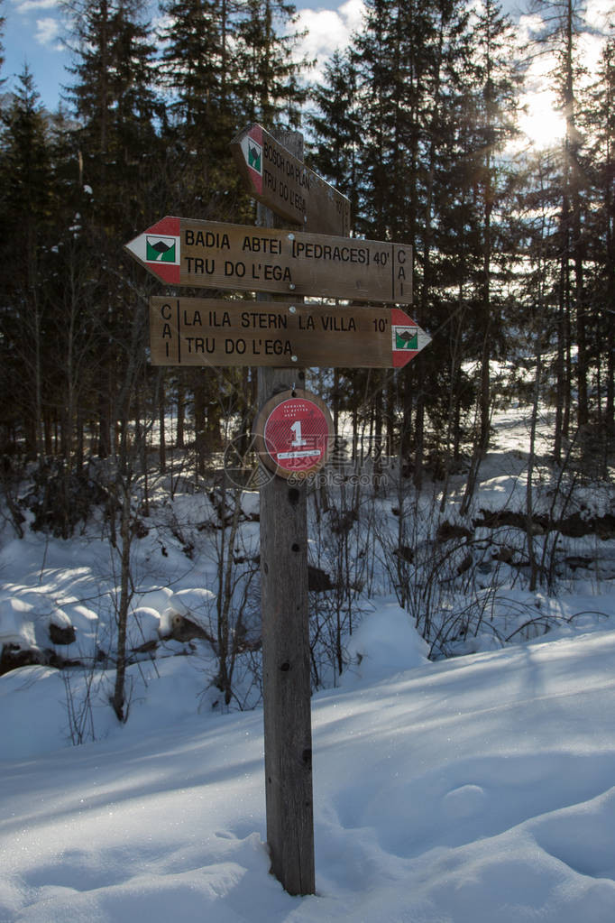 白雪覆盖的山间小道中的木制方向路径标志图片