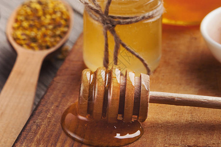 玻璃蜂蜜罐和木制桌上的花瓶图片