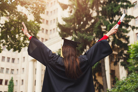 无法辨认的幸福女人在大学毕业那天拿着文凭和举手图片