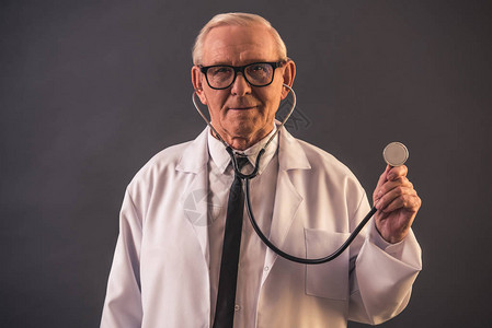 医用大衣和眼镜的英俊老医生使用听诊器图片