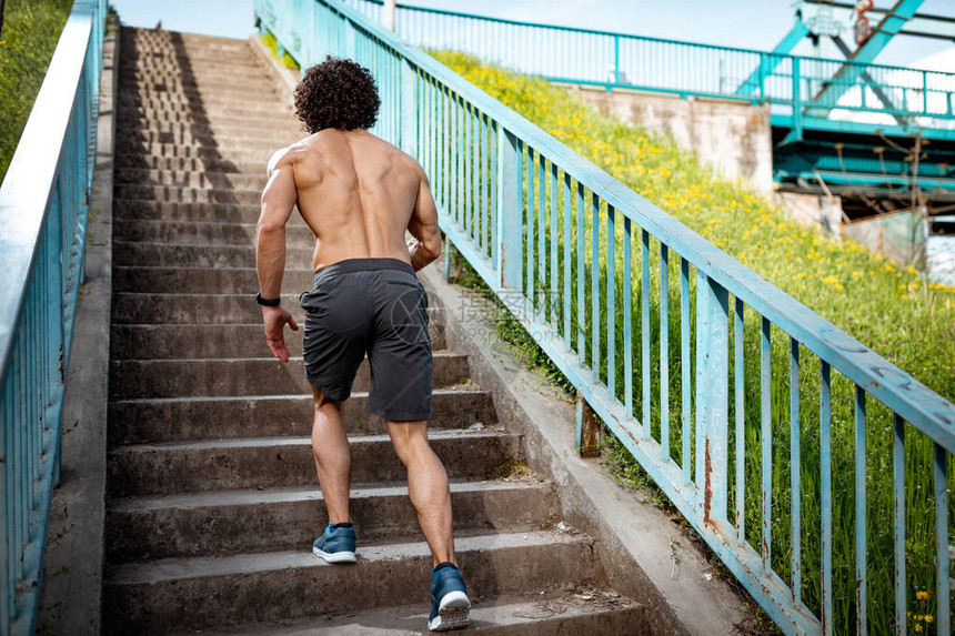 适合肌肉的年轻男跑步者在桥台阶上赤图片