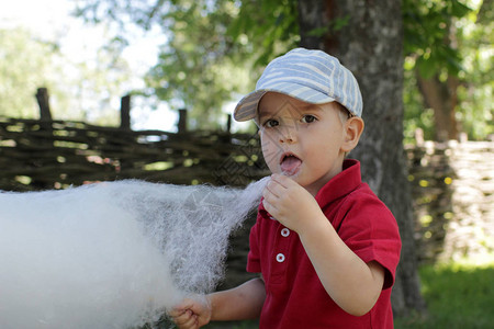 甜言蜜语有趣的小男孩在公园吃棉花糖背景