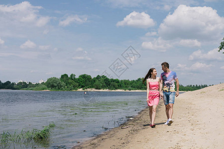 小情侣在河岸互相拥抱和微笑在沙滩上走来去图片