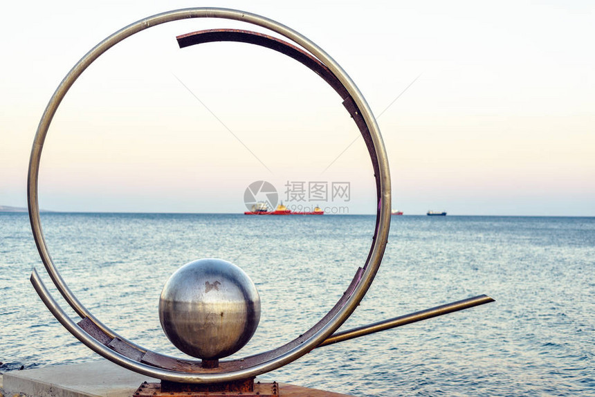 日落的景象是著名的金属环和球形纪念碑在港口附近海面图片