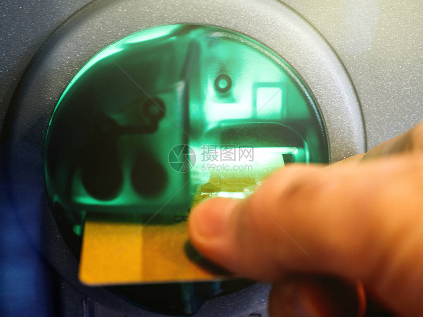 将借记卡插入自动柜员机ATM插槽的成年男子手的特写镜头图片