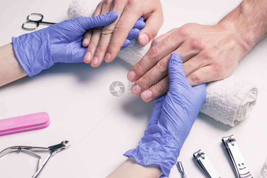 男人的修甲工戴橡胶手套的美容师用波图片