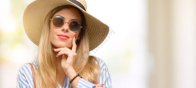 身戴太阳镜和暑假帽子的年轻女子思考图片