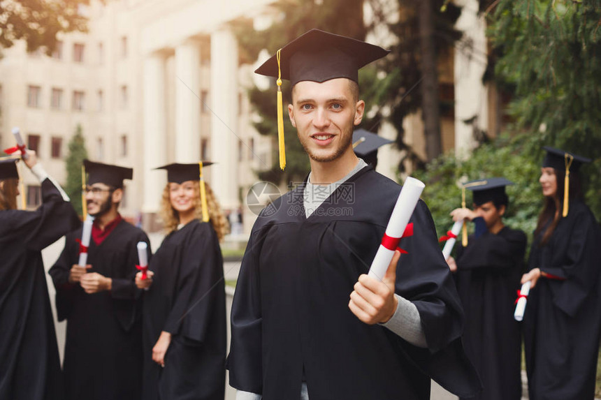 年轻的微笑男子在大学毕业那天与多民族学生站在一起教育资图片