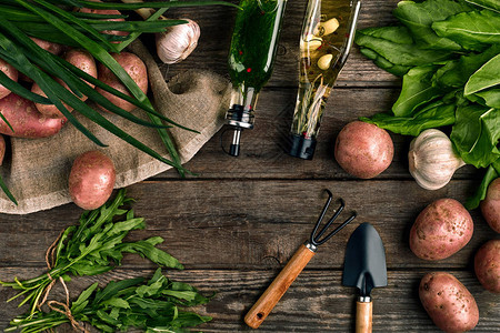 厨房木质背景的新鲜土豆油大蒜和辣味草药图片