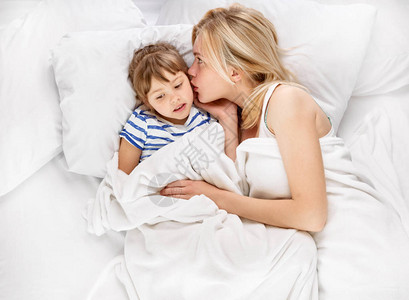欢笑的母亲和她的小女孩在床上低声语从图片
