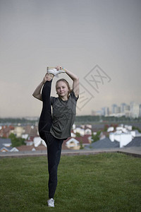 年轻女杂技演员站在腿上身挂在背景城市风景的麻图片