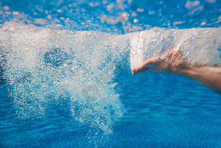 夏天在游泳池里游泳的男人的腿图片