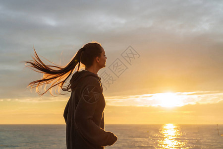 日落时长头发的女子在海上跑来背景图片