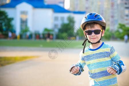 小男孩夏天在公园坐过山车戴头盔的快乐孩子学会滑冰图片