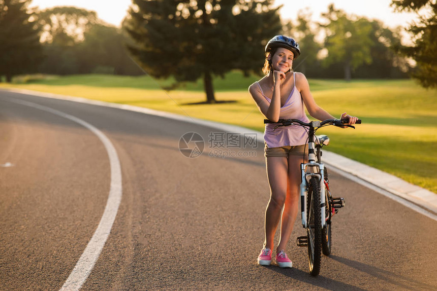 漂亮的女人骑自行车的人在户外摆着自行车在乡村道路上骑自行车的女孩夏图片