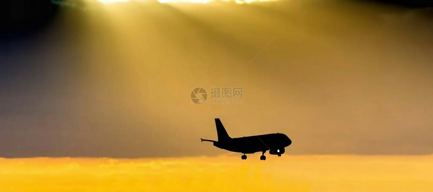 在深夜以美丽的金橙色日落背景在机场降落的客机图片