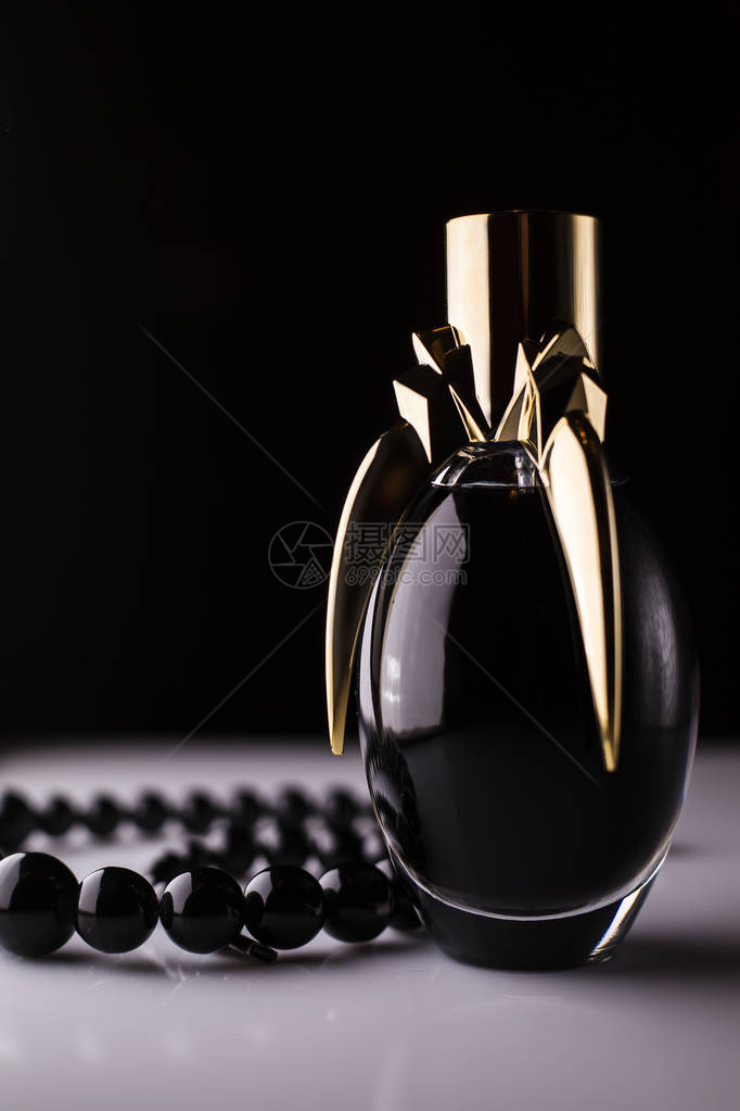 深色背景中带珍珠的黑色香水瓶图片