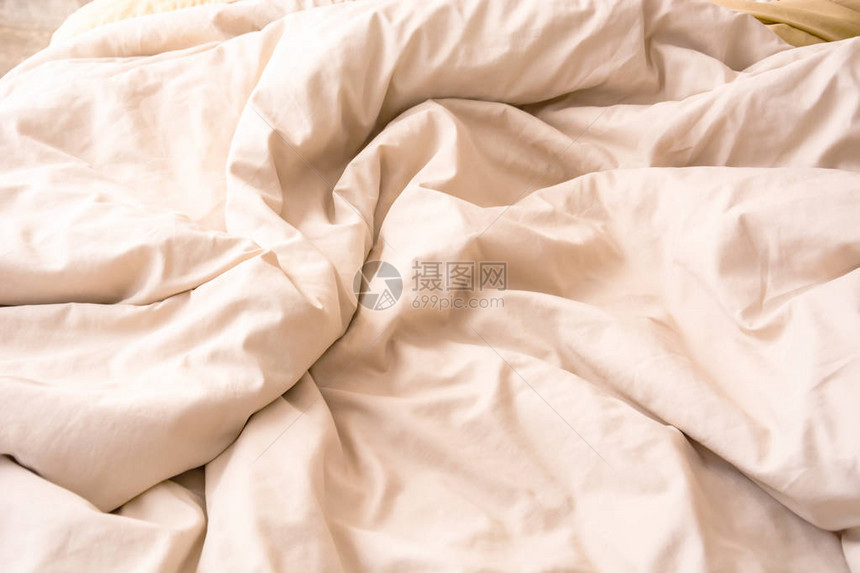 在漫长的夜晚睡觉后在床上起皱的奶油毛毯的顶视图图片