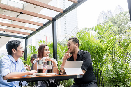 三个年轻快乐的亚洲朋友在现代自助餐厅户外吃喝越南咖啡的桌边图片