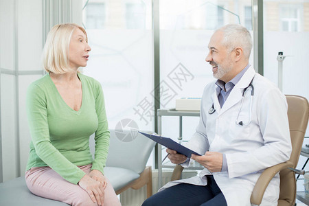 在门诊期间与她的治疗师交谈的绿色搭配中年长病人在图片