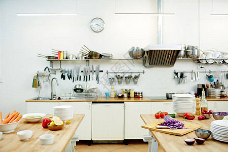 配有各种厨房用具和餐桌上新鲜蔬菜的现代餐厅厨房图片