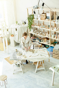 小型现代工作室和办公桌的年轻女子制作粘土玩具和供出售的图片
