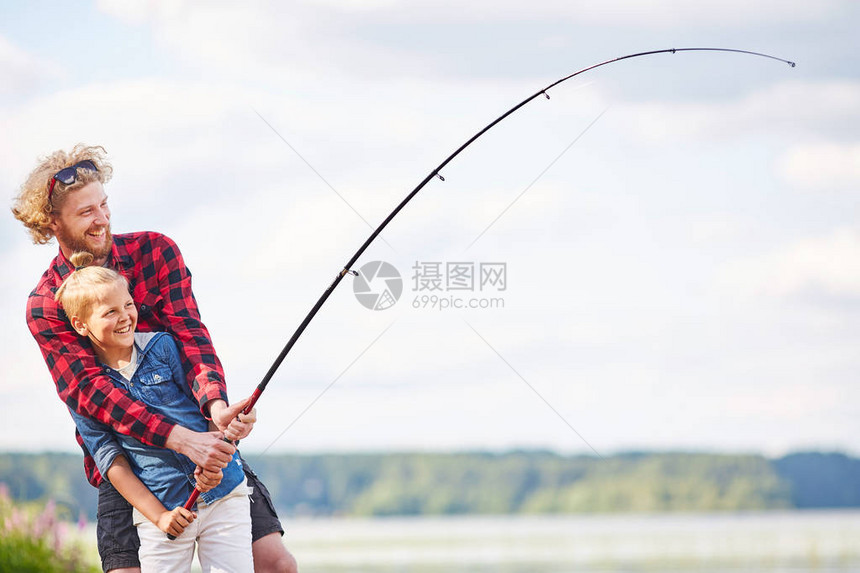 两个快乐的渔民带着棍子享受着夏天周末在湖图片