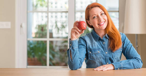 红发妇女在家里拿着红苹果图片