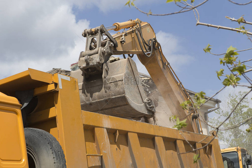 车轮上的挖掘机在自卸卡车的身中装载建筑垃圾和旧建图片